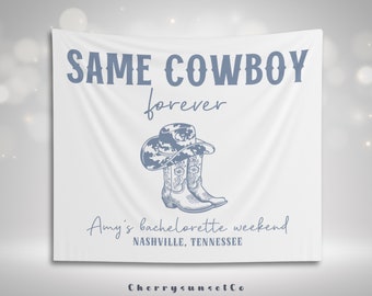 May include: White banner with blue text that reads "SAME COWBOY forever" with a drawing of a cowboy hat and boots. Below the text is "Amy's bachelorette weekend NASHVILLE, TENNESSEE" and the text "CherrySunsetCo" at the bottom.