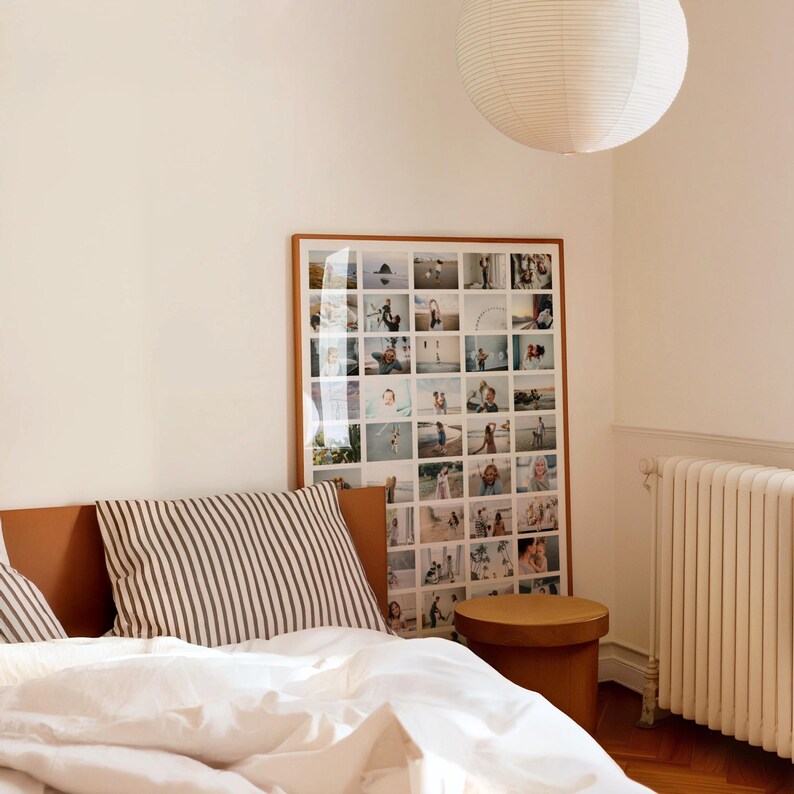 Op de afbeelding: Een slaapkamer met een grote ingelijste fotocollage, een gestreept kussen en een ronde houten bijzettafel. Het bed heeft een wit dekbed en een bruin lederen hoofdbord. Een witte papieren lantaarn hangt aan het plafond.
