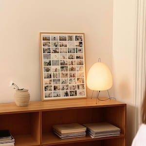 Op de afbeelding: Een ingelijste fotocollage op een houten kast. Een witte papieren lantaarnlamp met zwarte poten staat op de kast. Een kleine vaas met een witte bloem staat ook op de kast.
