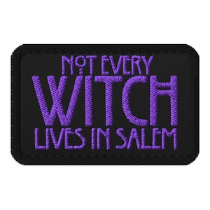 May include: Black rectangular patch with the embroidered text "NOT EVERY WITCH LIVES IN SALEM" in purple. The patch has a black border and is likely for clothing or accessories.