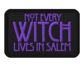 May include: Black rectangular patch with the embroidered text "NOT EVERY WITCH LIVES IN SALEM" in purple. The patch has a black border and is likely for clothing or accessories.