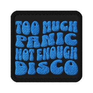 May include: Embroidered patch with the text "TOO MUCH PANIC NOT ENOUGH DISCO" in blue bubble letters on a black background. The patch has a black border and a textured appearance.
