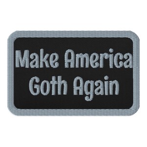 May include: Embroidered patch with the phrase "Make America Goth Again" in gray lettering on a black background. The patch has a rectangular shape with a gray border.