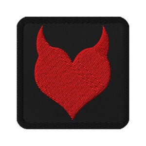 May include: Square black embroidered patch featuring a red heart-shaped design with two upward-curving horns. The patch has a stitched border and is likely for clothing or accessories.