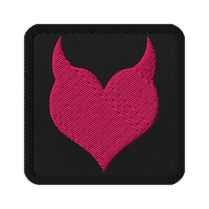 May include: Embroidered patch featuring a pink heart-shaped design with two upward-curving horns on a black square background. The patch has a stitched border.