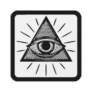 May include: Embroidered patch featuring a black and white all-seeing eye within a triangle, radiating lines on a white background. The design is enclosed in a black square with rounded corners. The eye is detailed with intricate shading.