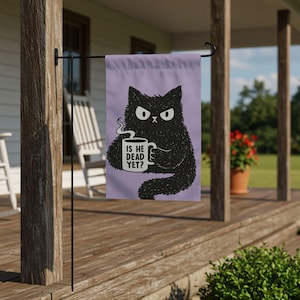 May include: A rectangular garden flag with a light purple background featuring a black, fluffy, grumpy-looking cat holding a white mug with steam rising from it. The mug has the text IS HE DEAD YET? printed in black capital letters on the front.
