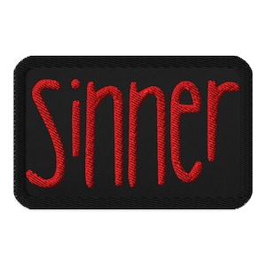 May include: Black rectangular patch with the word "Sinner" embroidered in red thread. The text is in a bold, stylized font, and the patch has a stitched border.