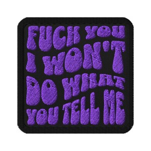 May include: Embroidered patch with the phrase "FUCK YOU I WON'T DO WHAT YOU TELL ME" in purple, stylized lettering on a black square background. The patch has a black border.
