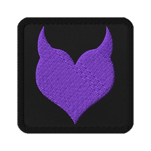 May include: Embroidered patch featuring a purple stylized heart shape on a black square background. The heart design has a textured appearance, and the patch has a black border.