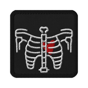 May include: Embroidered patch featuring a white skeletal rib cage design with a red heart on a black square background. The patch has a stitched border. Ideal for jackets, bags, or other fabric items.