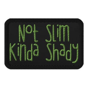May include: Black rectangular patch with green embroidered text that reads "Not Slim Kinda Shady". The patch has a black border and is likely designed to be sewn or ironed onto clothing or accessories.