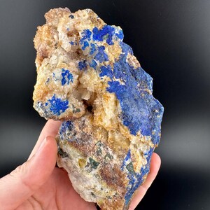 May include: A rough, natural specimen of blue azurite crystals embedded in a matrix of white calcite. The azurite crystals are clustered together, creating a visually appealing contrast against the white calcite.