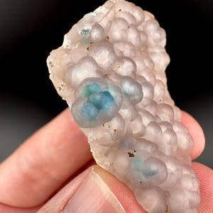 May include: A cluster of translucent, light purple, bubble-like formations with blue and green inclusions. The cluster is on a white background.