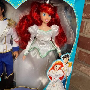 May include: Ariel doll from Disney's The Little Mermaid, in a white wedding dress with a mint green trim. The doll has red hair and is in a box with Prince Eric. The box is blue with gold stars and the words "Limited Edition".