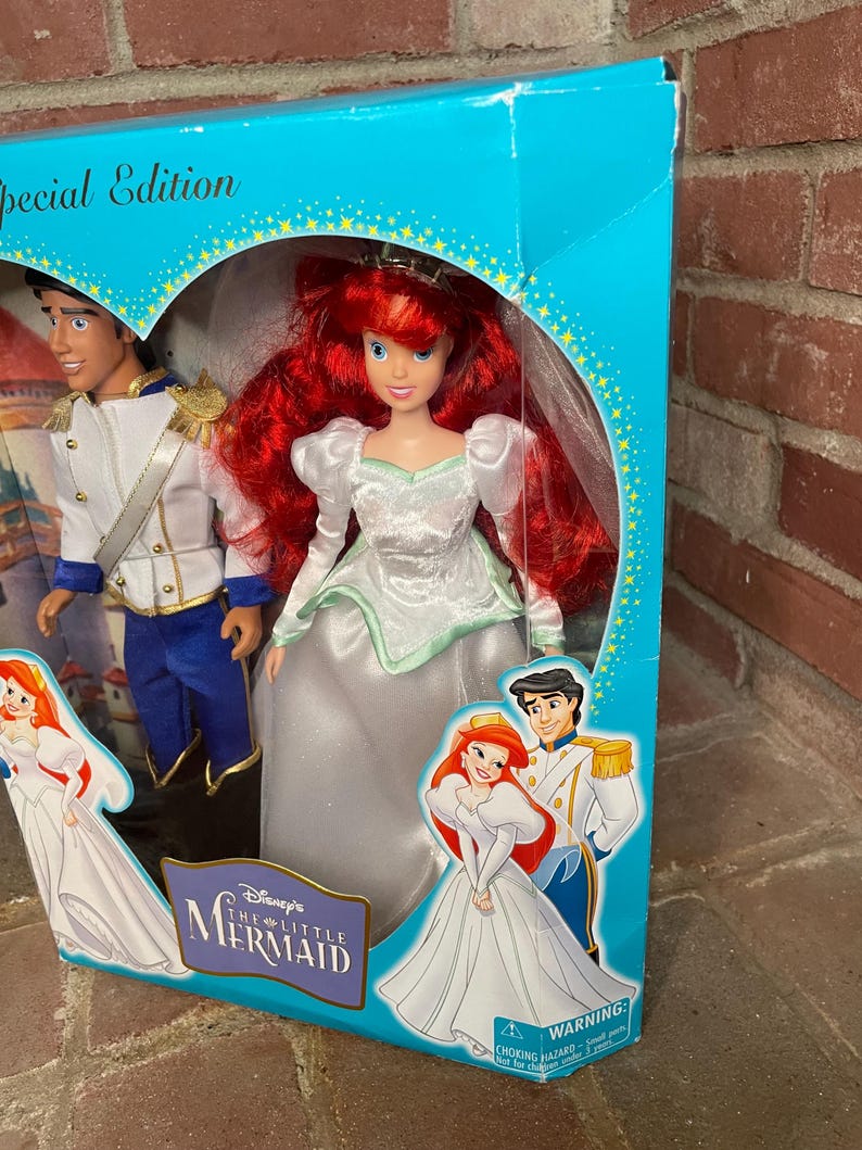 May include: A Special Edition Disney's The Little Mermaid doll set featuring Ariel in a white gown with red hair and Prince Eric. The box is turquoise with gold stars and illustrations of the characters.