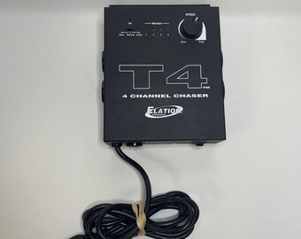 May include: Black T4 4-Channel Chaser by Elation. The device has a speed control knob, monitor lights, and input jacks. The power cord is coiled and secured with a rubber band. The device is on a white surface.