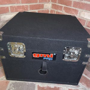 May include: Black rectangular case with silver hardware and a black strap with a metal ring. The case has a "gmi PRO" logo in red and blue.