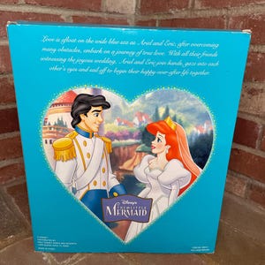 May include: A teal box featuring Disney's The Little Mermaid. The box art depicts Ariel and Eric in a heart-shaped frame, with text describing their love story. The box has text that reads "Love is afloat on the wide blue sea..."