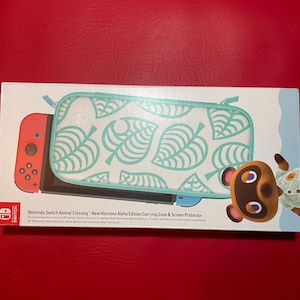 May include: Nintendo Switch Animal Crossing: New Horizons Aloha Edition carrying case and screen protector. The case is white with a teal leaf pattern and a teal zipper. The box features the Nintendo Switch logo and a character from the game.