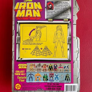 May include: A Spider-Woman action figure from the Marvel Comics Iron Man series. The figure is posed with her arms outstretched, holding a web. The figure is wearing a red and black costume with a spider symbol on her chest. The packaging features a yellow background with the Marvel Comics logo and the words "Iron Man" in large, bold letters. The back of the packaging includes a description of the character and instructions on how to play with the figure.