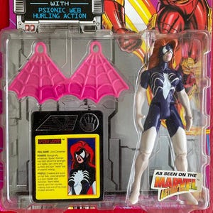 May include: A Spider-Woman action figure with pink web wings, a blue and white suit, and red hair. The figure is packaged in a plastic blister pack with a card featuring a comic book style illustration of Spider-Woman. The card includes the text "SPIDER-WOMAN", "WITH PSIONIC WEB HURLING ACTION", "REAL NAME: Julia Carpenter", "POWERS: Biologically enhanced. Spider-Woman has both abnormal strength and agility, can climb any surface and spin 'webs' out of psychic energy", "PROFILE: Creative and quick on her boot Julia Carpenter is a born leader and tactician. Stark relies heavily upon her counsel, making Julia one of his most trusted advisers."