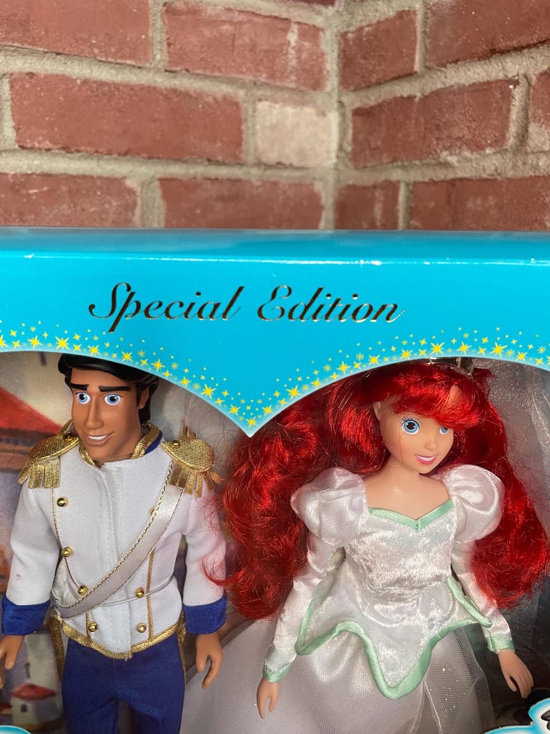 May include: A Special Edition box set featuring two dolls: Prince Eric in a white jacket with gold accents and blue pants, and Ariel in a white dress with red hair. The box has a blue top with the words "Special Edition".