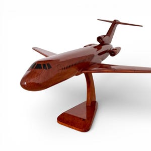 May include: A detailed wooden model airplane, featuring a polished, reddish-brown finish. The model includes wings, tail, and engines, mounted on a matching wooden stand. The airplane is a decorative item.
