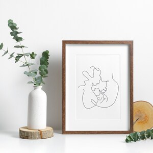 May include: A framed black and white line drawing of a family with a parent holding a child. The drawing is in a brown frame and is on a white background.