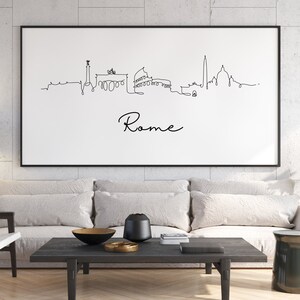 May include: A black and white line drawing of the Rome skyline with the word "Rome" written below. The drawing is framed and hanging on a white wall above a gray couch.