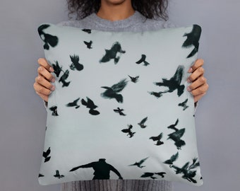 Puede incluir: Una almohada con un fondo azul claro y un patrón de pájaros negros en vuelo. Los pájaros están en silueta contra el fondo azul claro.