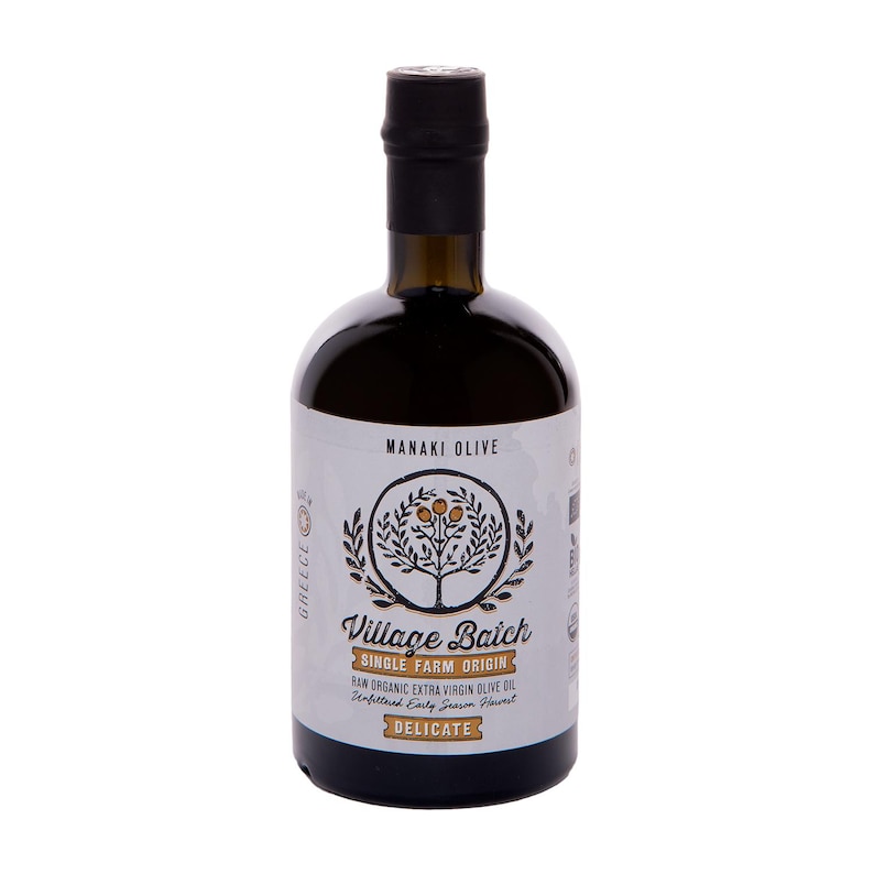 K&ouml;nnte beinhalten: Eine dunkle Glasflasche mit Manaki Olive Village Batch nativem Oliven&ouml;l extra und schwarzem Verschluss. Das wei&szlig;e Etikett zeigt eine kreisf&ouml;rmige Baumillustration, den Text Village Batch, Single Farm Origin und das Wort Delicate.