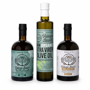 K&ouml;nnte beinhalten: Drei Glasflaschen mit Village Batch rohem Bio-Oliven&ouml;l extra vergine. Die mittlere Flasche ist hoch und hat einen wei&szlig;en Verschluss, w&auml;hrend die beiden k&uuml;rzeren Flaschen an den Seiten schwarze Verschl&uuml;sse haben. Etiketten mit Text.