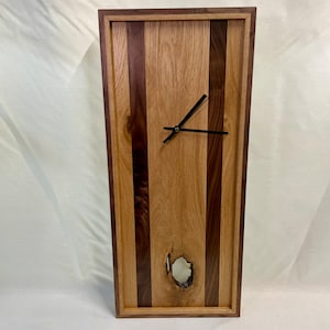 May include: A wooden wall clock with a natural wood and walnut finish. The clock face has black hands and is surrounded by a wooden frame.