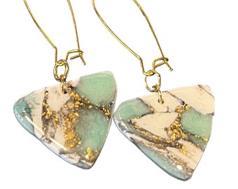 May include: A pair of gold triangle earrings with a white, green, and gold marbled design.