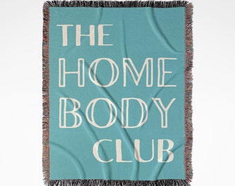 May include: A turquoise blue woven throw blanket with the text "THE HOME BODY CLUB" in white.