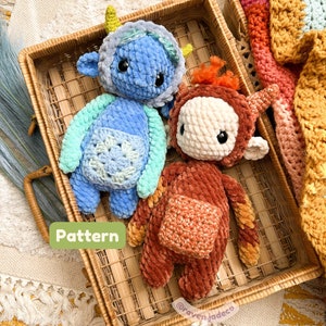 Puede incluir: Dos juguetes de peluche tejidos a crochet en una cesta de mimbre. Uno es azul con un babero tejido a crochet verde y blanco y el otro es naranja con un babero tejido a crochet marrón. El texto "Pattern" es visible en la imagen.