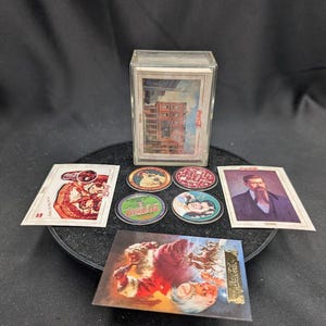 May include: A collection of vintage Coca-Cola trading cards and promotional items. The items include cards with images of buildings, portraits, and advertisements. There are also several round promotional items with Coca-Cola branding.