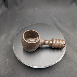 Peut inclure: Un casse-noix marron avec une poignée texturée et un mécanisme à vis. Le casse-noix est fait d'un matériau brun foncé et est conçu pour casser les noix. Le casse-noix est sur une surface gris foncé.