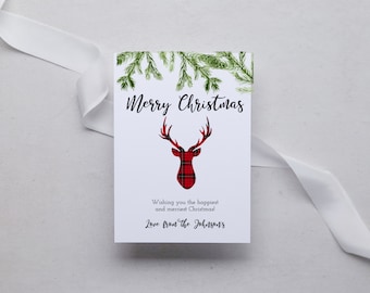 May include: A Christmas card with a red and black plaid reindeer silhouette and green pine branches. The card reads "Merry Christmas" and "Wishing you the happiest and merriest Christmas! Love from the Johnsons."