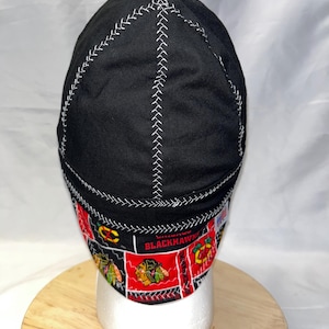 Puede incluir: Gorra de soldador negra con costuras blancas. La gorra presenta una banda estampada con el logotipo de los Blackhawks de Chicago en rojo, negro y amarillo. Diseñada para proteger la cabeza y el cabello de chispas y calor.