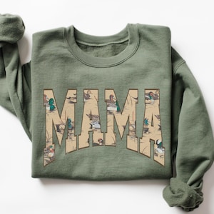May include: A green sweatshirt with the word "MAMA" printed on the front. The letters are filled with a pattern of ducks and reeds.