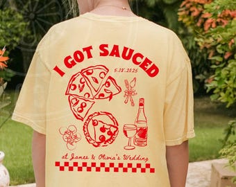 May include: A yellow t-shirt with the text "I got Sauced 5.14.2025 at James & Olivia's Wedding" in red. The shirt features a graphic of pizza slices and a glass of wine.