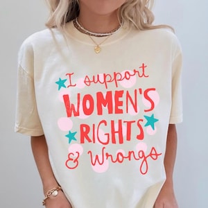 Peut inclure: T-shirt de couleur ivoire avec l'inscription "I support WOMEN'S RIGHTS & Wrongs" en rouge et rose. Le motif comprend des pois roses et des &eacute;toiles turquoise. Style d&eacute;contract&eacute; et unisexe.