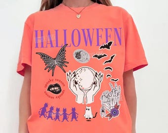 May include: A bright salmon-colored t-shirt with the word "HALLOWEEN" in purple block letters. The shirt features various spooky graphics, including bats, a spiderweb, a crystal ball, and a skeleton hand. The words "spooky season" are also present.