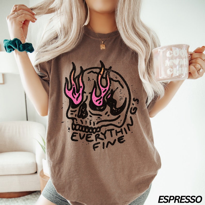May include: Brown t-shirt with a graphic of a skull with flames for eyes and the text "EVERYTHING'S FINE".