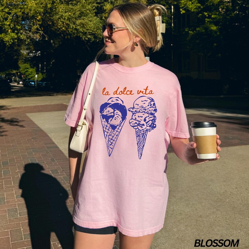 May include: A pink t-shirt with the text "la dolce vita" in orange and a graphic of two ice cream cones with blue ice cream.