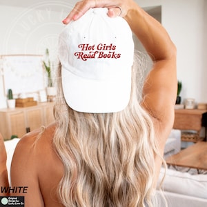 Op de afbeelding: Een witte baseball cap met de tekst "Hot Girls Read Books" in een retro rode letter. De cap is een klassieke stijl, perfect voor casual wear. De afbeelding toont de achterkant van een persoon die de cap draagt.