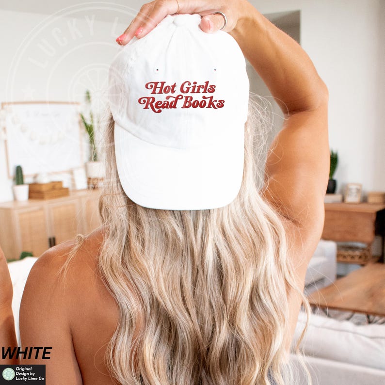Op de afbeelding: Een witte baseball cap met de tekst "Hot Girls Read Books" in een retro rode letter. De cap is een klassieke stijl, perfect voor casual wear. De afbeelding toont de achterkant van een persoon die de cap draagt.