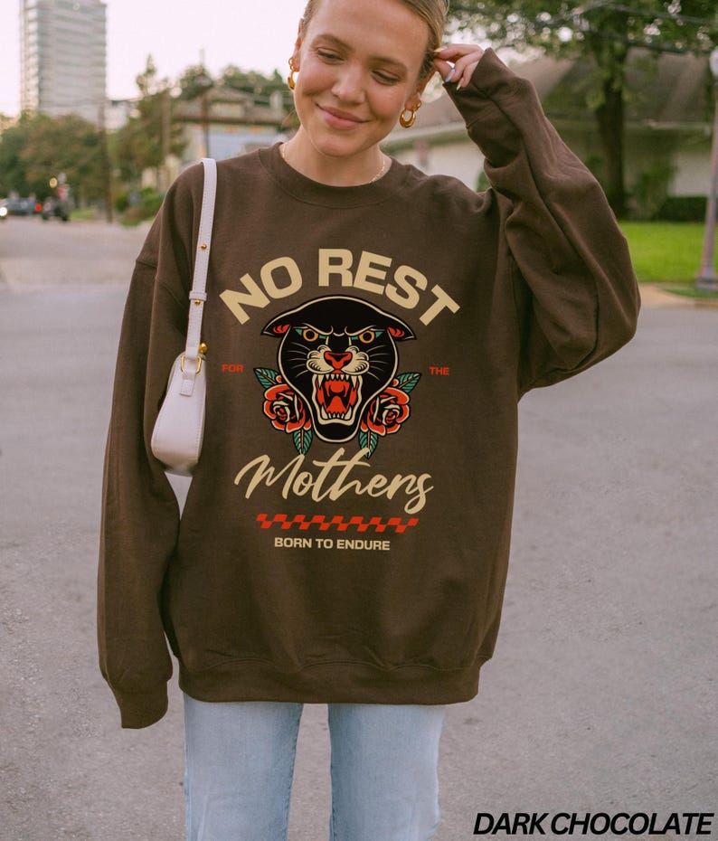Op de afbeelding: Een bruin sweatshirt met een zwarte panter afbeelding en de tekst "No Rest for the Mothers Born to Endure".